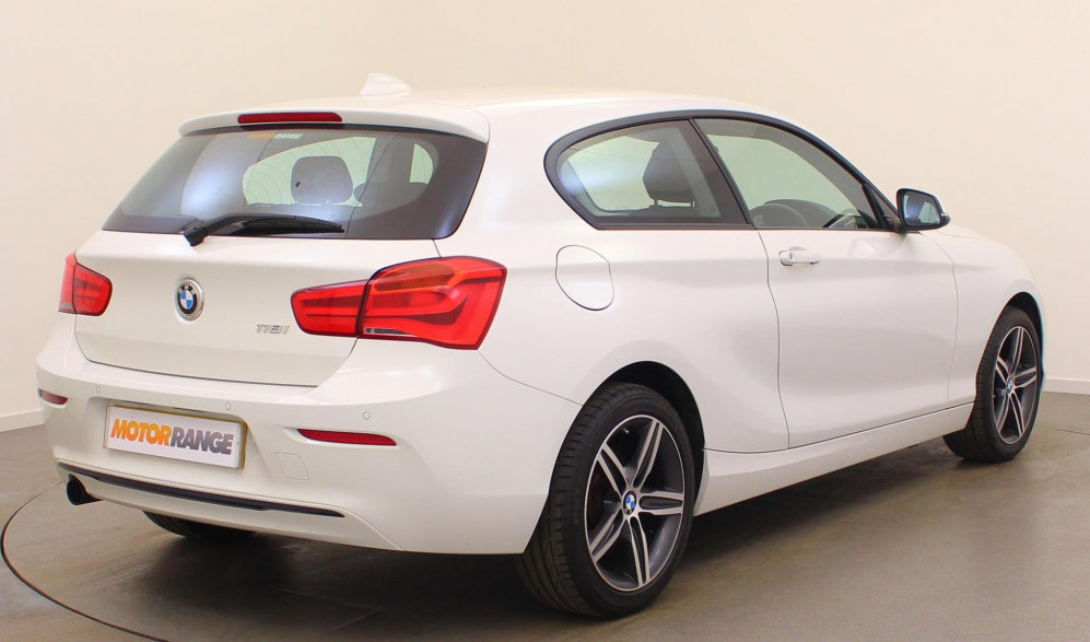 Rear-side view of white BMW 1 Series parked in showroom